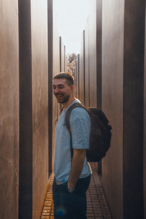 A man with a large backpack is standing in a long, narrow hallwayの写真素材