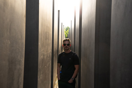 A man who is wearing stylish sunglasses stands confidently in a narrow and somewhat cramped hallway, creating an intriguing atmosphereの写真素材