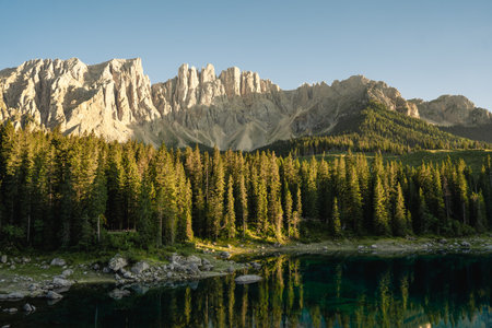 A beautiful lake that is completely surrounded by lush green trees, with a majestic mountain prominently visible in the distant backgroundの写真素材