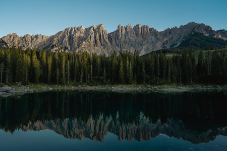 Majestic mountains are beautifully reflected in a tranquil lake that is surrounded by lush green trees, creating a serene natural landscapeの写真素材