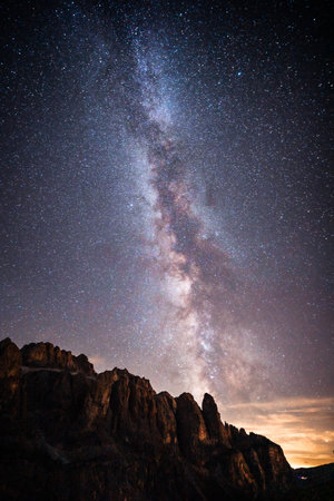 A stunning night sky filled with countless stars, illuminating a majestic mountain that stands tall in the foreground of this beautiful sceneの写真素材