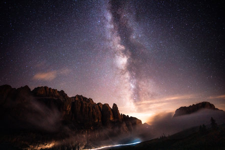 A stunning night sky filled with countless stars, illuminating a majestic mountain that stands tall in the foreground of this beautiful sceneの写真素材