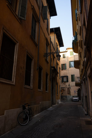 There is a narrow street where a bicycle is parked alongside its edge, creating a quaint scene with buildings and a serene atmosphereの写真素材