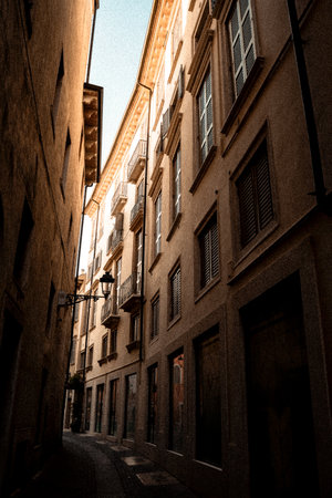 A narrow and quaint alleyway that exists between two distinctive buildings, both adorned with charming shutters on their windowsの写真素材