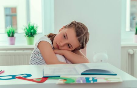 sad little school girl while homeworkの写真素材