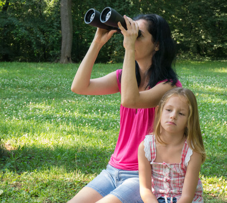 mother and her daughter looking through binoculars in the parkの写真素材