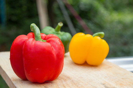 red green sweet peppers on wooden background