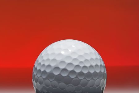 golf ball isolated against red backgroundの写真素材