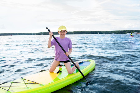 A 10-year-old boy rides a SUP board on a river or lake aloneの写真素材