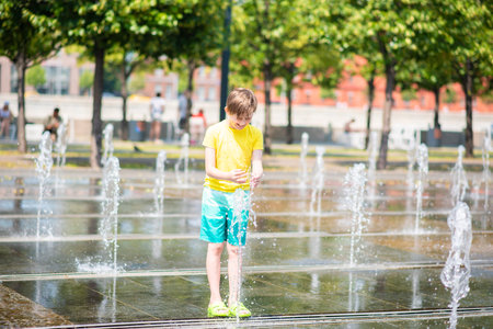 happy boy playing in dry fountain in summerの写真素材