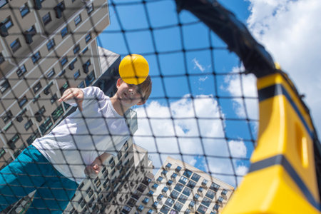Boy playing basketball in New York City, wearing a yellow cap and blue shorts.の写真素材
