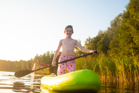 A 10-year-old boy rides a SUP board on the river aloneの写真素材