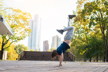 child, teenager dancing in a park in the city. An 11 year old boy is doing breakdancing outside on a...
