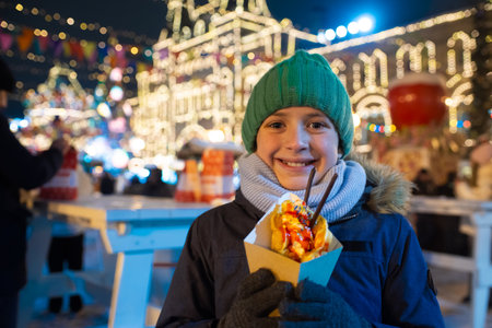 happy boy at christmas market, festival, fair holding sweet hong kong fawns in his hands, going to...