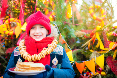 smiling boy going to eat pancakes at the traditional Russian festival dedicated to the meeting of...