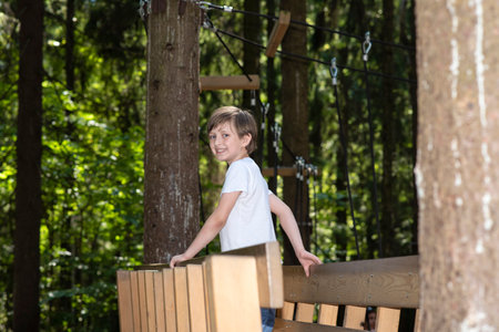 Cute little boy having fun in a rope park on a sunny summer dayの写真素材