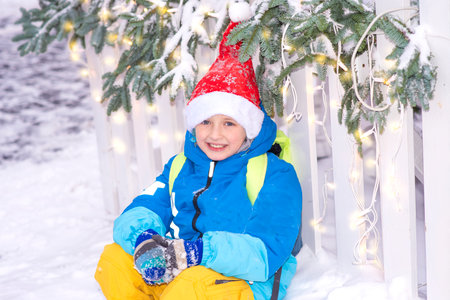 Little boy in a red cap and blue jacket on a background of a Christmas treeの写真素材