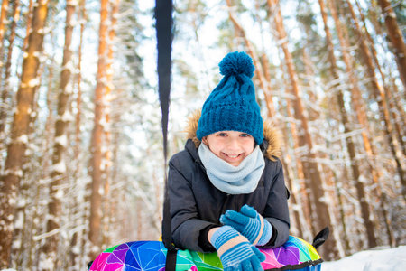 Little girl having fun on a sled in the winter forest. Winter activities for children.の写真素材