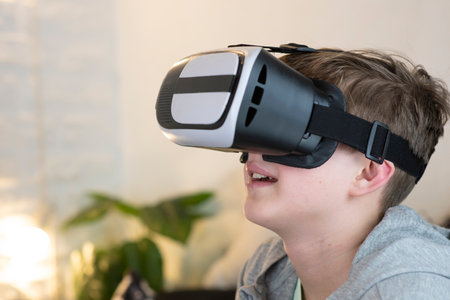 portrait of a happy 11 year old boy, child wearing virtual reality glasses at home, inside.の写真素材