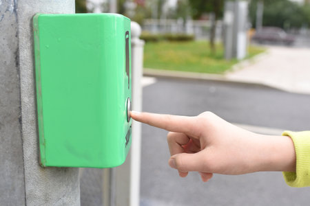 finger presses button to turn off green light of traffic lightの写真素材