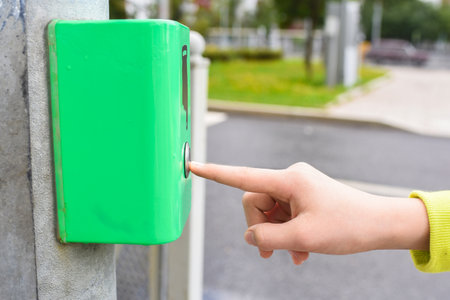 A finger presses a button to turn on the green light of a traffic light. Under the button is the inscription "wait" in Russian.の写真素材