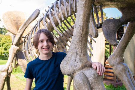 A teenage boy in a blue T-shirt with a dinosaur skeleton.