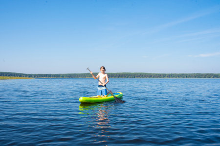 Young woman paddling on a green kayak on the lake.