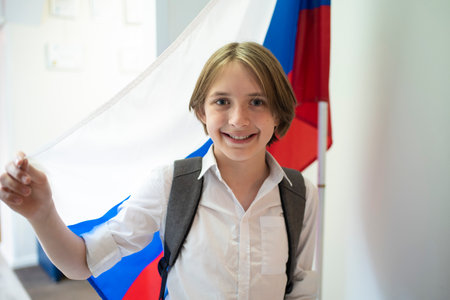 An 11-year-old schoolboy stands next to the flag of the Russian Federation at school.の写真素材