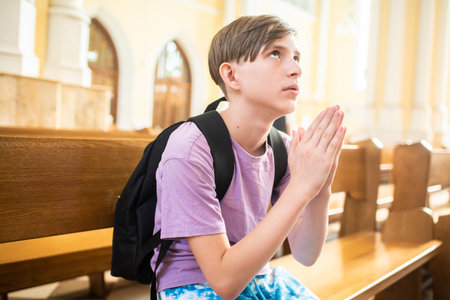 Teenage boy praying in the church. Education and religion concept.の写真素材