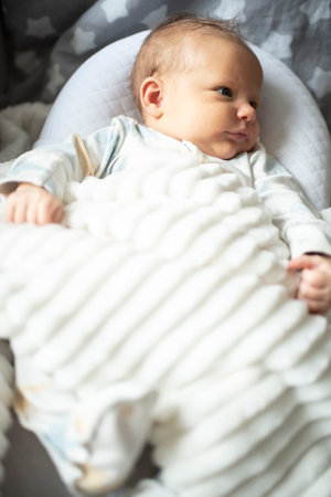 Newborn baby boy lying on a soft blanket in the bed.