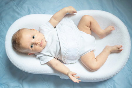 Portrait of baby boy lying in nursery for newborns. Infant in white bed. Baby is 2 months old. Happy baby morning.の写真素材
