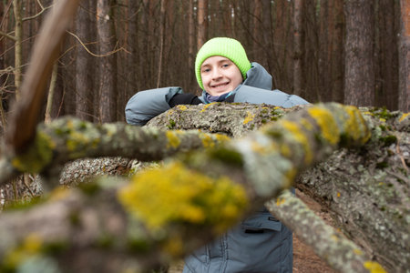 Portrait of a 12 year old boy in a green hat and a gray jacket. The teenager stands in front of a...