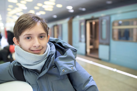 portrait of a 12 year old boy in winter clothes, scarf. the child is on the platform, metro stationの写真素材