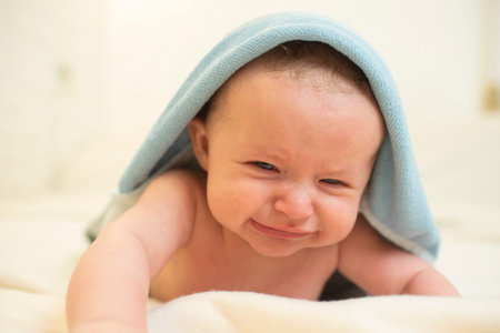 Portrait of cute newborn baby wrapped in blue towel on bedの写真素材