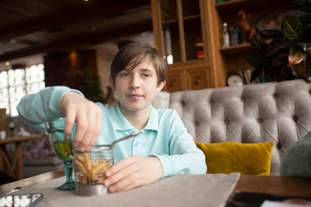 boy eating French fries in a restaurant or cafeの写真素材