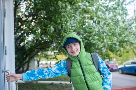 a boy opens the door to the entrance in spring, the child returns from school in spring aloneの写真素材