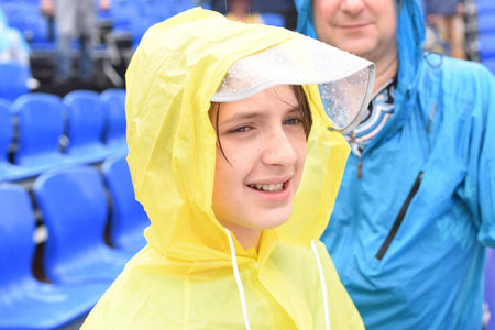 boy in yellow raincoat with hood during rain in stands.の写真素材
