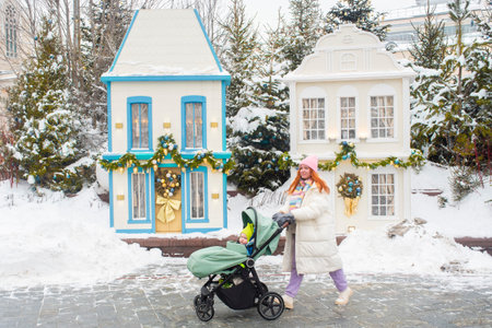 Mother with baby stroller walking past festive Christmas street decorations in winter Moscow