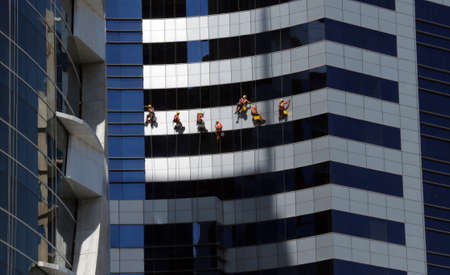 Workers on the facade of a skyscraperの写真素材