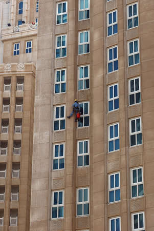 Worker hanging on the wall of a high-rise building.の写真素材