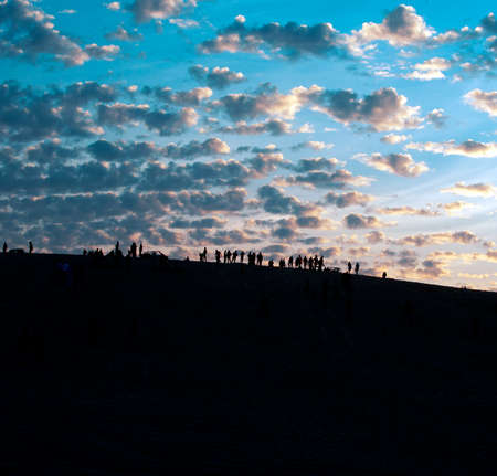 Silhouettes of people on top of the dunes at sunsetの写真素材