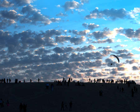 Paragliders flying over the sand dunes at sunset.の写真素材