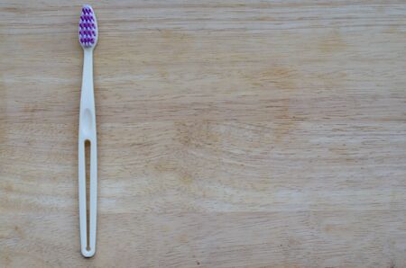 White or cream colored bamboo toothbrush on wood background. Zero waste, biodegradable material,...