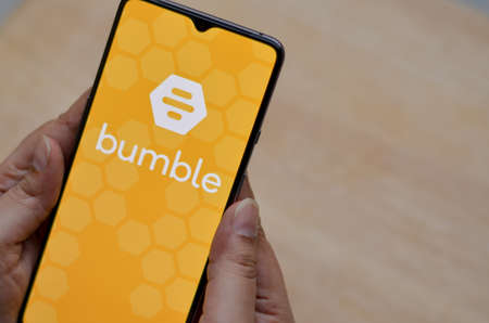 London, England, United Kingdom, 2020. Flat lay with wooden background and Bumble app logo on...