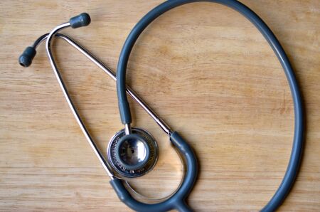 Flat layout of a stethoscope placed on a wooden table backgound. Doctors use this instrument to hear the hearbeats and pulse to diagnose any illness in his examinationの写真素材