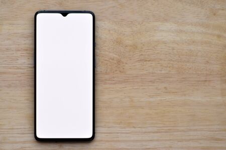 A mobile phone showing empty white screen kept over a wooden background. Advertising internet app /...