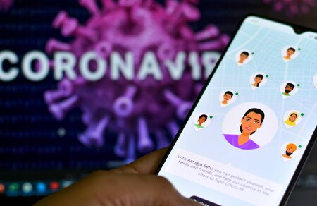 New Delhi, India, 2020. Aarogya Setu app, developed by government of India to track the Covid-19 status, Logged in on a mobile infront of a screen showing microscopic 3D illustration of Corona Virusの写真素材