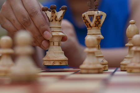 Close up of white chess pieces with Queen picked in player's hands. Concept - idea, strategyの写真素材