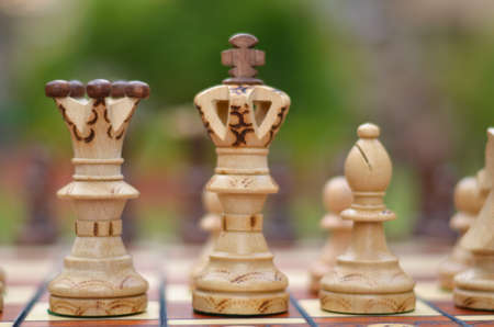 Close up of white chess pieces with focus on queen and king and bishop in straight line and pawns blurred out in background and foreground. Concept - idea, strategyの写真素材