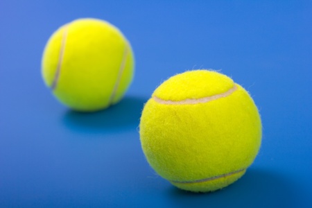 Two tennis balls on a blue background.Focus in the foreground.の写真素材
